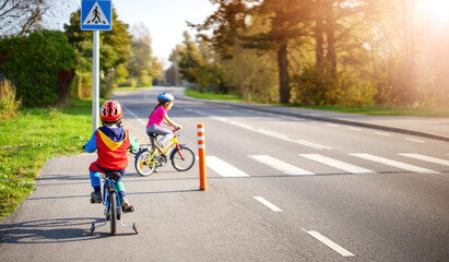 Cute children riding on bicycles on asphalt road in summer. - 424016810