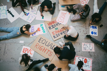 Directly above of male and female activists preparing posters for social movement