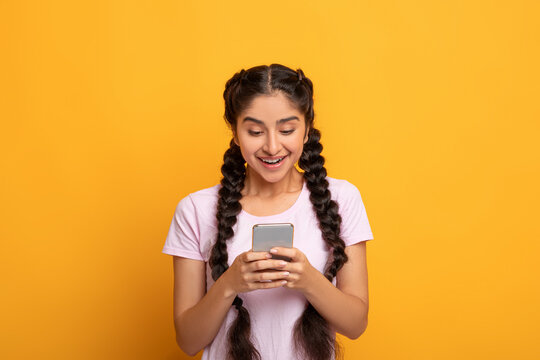 Smiling Indian Woman Using Smart Phone Isolated On Yellow Background