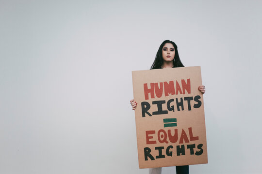 Female activist with human rights signboard against white wall
