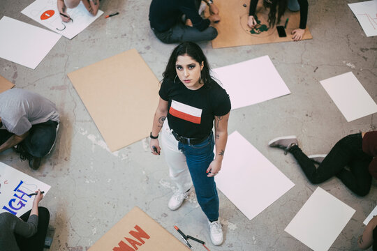 Portrait of woman standing while male and female activist preparing signboards in building