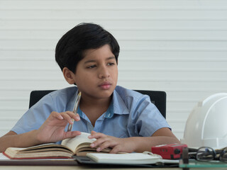 Handsome Indian boy thinking while doing homework or studying.