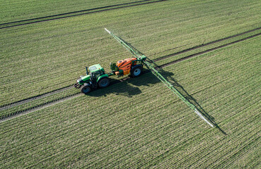 Luftbild - Traktor mit Pflanzenschutzspritze in einem jungen Getreidebestand im Einsatz,...