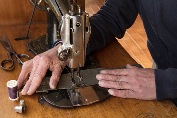 Sewing process. Close up of old Man's hands behind sewing. Sew workshop. textile vintage sewing industrial on wood table