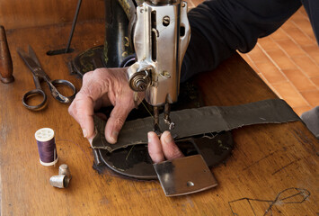 Old man's hands behind sewing. Fingers on needle. Sew workshop. textile vintage home sewing on wood table