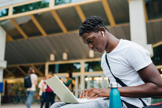 Male College Student Studying Online On Laptop In University Campus