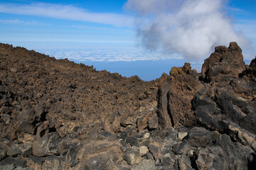Fototapeta na wymiar Rocas volcánicas del volcán Teide en la isla de Tenerife, Islas Canarias, España. Al fondo un mar de nubes sobre el océano Atlántico.