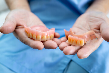 Asian senior or elderly old woman patient holding to use denture in nursing hospital ward, healthy strong medical concept