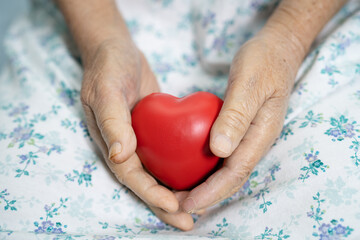 Asian senior or elderly old lady woman patient holding red heart in her hand on bed in nursing...