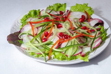 Vegetarian salad of radish, spinach, red onion and bell pepper and cucumber. On a light background.