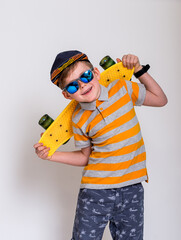 Funny child in sunglasses and skateboard in striped yellow shirt. fashionable little kid boy in sun glasses. stylish kid in yellow shoes. fashion children