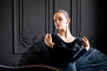 Portrait of young ballerina girl in black tutu on dark background