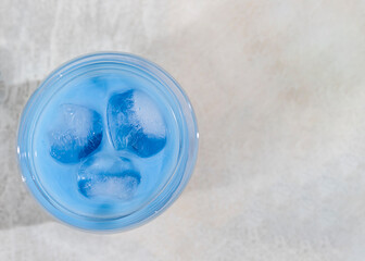 Cold milk Iced latte Matcha tea in a glass with ice cubes on a gray table.