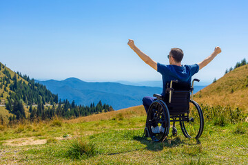 Optimistic handicapped man sitting on wheelchair on the mountains