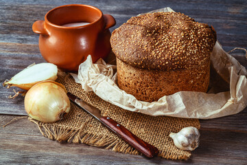 Traditional bread with a crust and a pot of sour cream on a wooden board