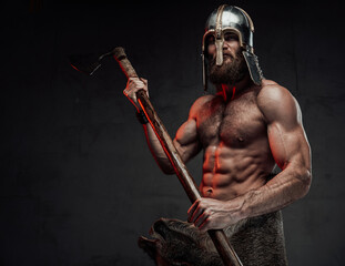Viking with naked torso and beard posing in dark background