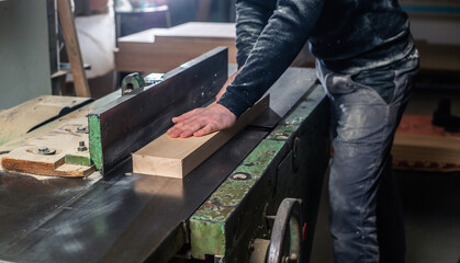 Professional carpenter milling the wood on the  huge saw for a modern furniture, joinery and woodwork concept