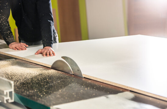 Professional carpenter cutting the wood on the  huge saw for a modern furniture, joinery and woodwork concept