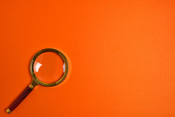 Magnifying glass on a bright orange background.