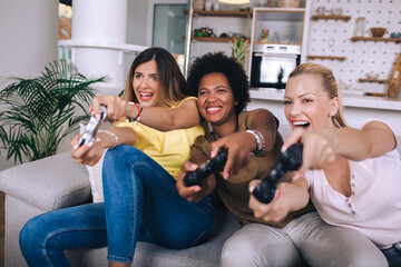 Portrait of happy women friends playing video games at home. © Mediteraneo