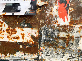 Torn poster on rust metal texture. Old grungy street wall with ripped rock concert advertisements.