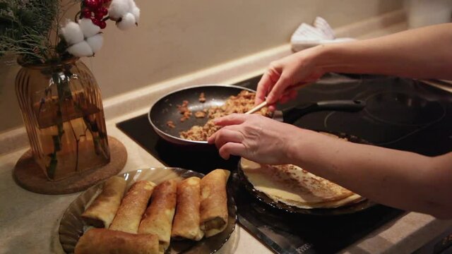 Cooking homemade Russian pancakes Bliny with meat on Shrovetide - Maslenitsa. Woman cooks pancakes in her kitchen
