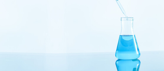 Laboratory glassware with blue liquid on white background