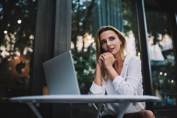 Dreamy woman at table with laptop