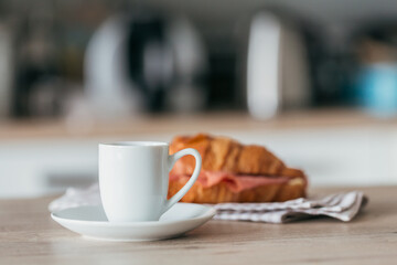 breakfast of coffee and croissant sandwich stuffed with salami