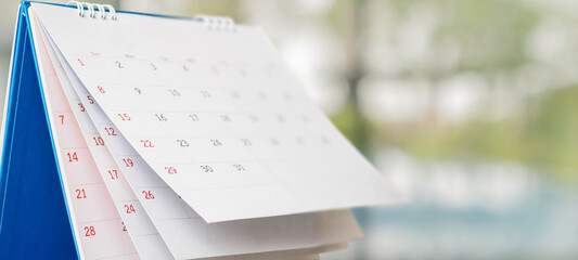 Close up white paper desk calendar with blurred bokeh background appointment and business meeting concept