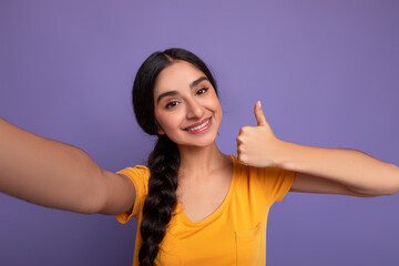 Indian woman taking selfie, showing thumbs up