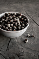 Black currant covered with frost on a gray concrete background in a gray plate