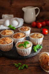 Cupcakes for snacks on a wooden board on a background of cherry tomatoes and eggs with basil
