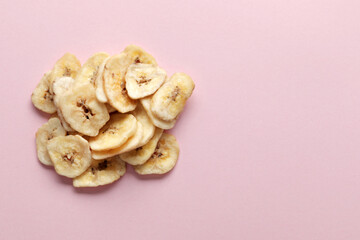 Composition with sweet dried banana slices on a pink background. Dried fruit as healthy snack