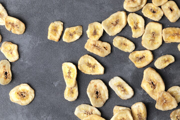 sweet banana slices on grey background, top view with space for text. Dried fruit as healthy snack