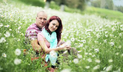 Fototapeta premium Couple in love guy and girl in a field of white daisies and green grass
