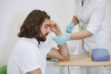 Fototapeta premium Nurse taking blood sample from patient at the doctors office