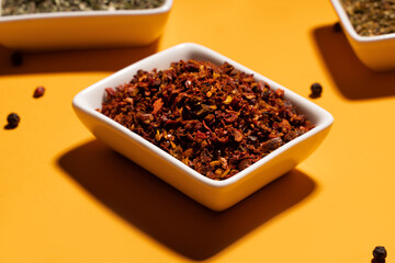 Paprica spice in white bowl on orange background