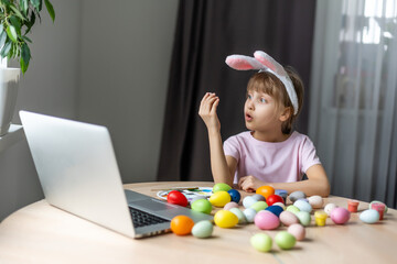 Little girl with her bunny using computer together preparing for easter