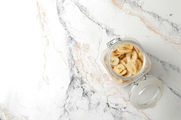 plate with banana slices on marble table, top view. Dried fruit as healthy snack