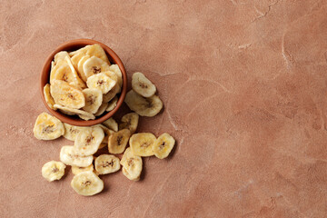 Bowl with sweet banana slices on а background, top view with space for text. Dried fruit as healthy snack