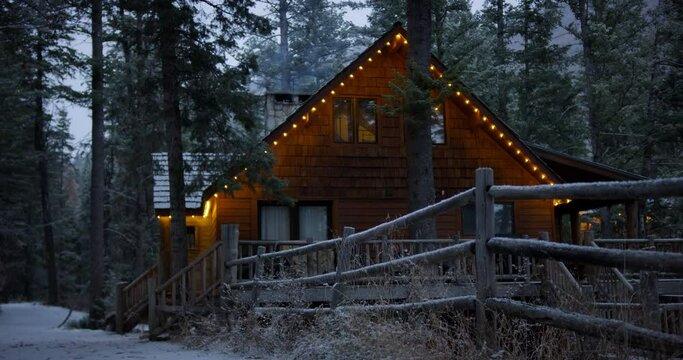 Low angle, log cabin with holiday lights during forest snowstorm