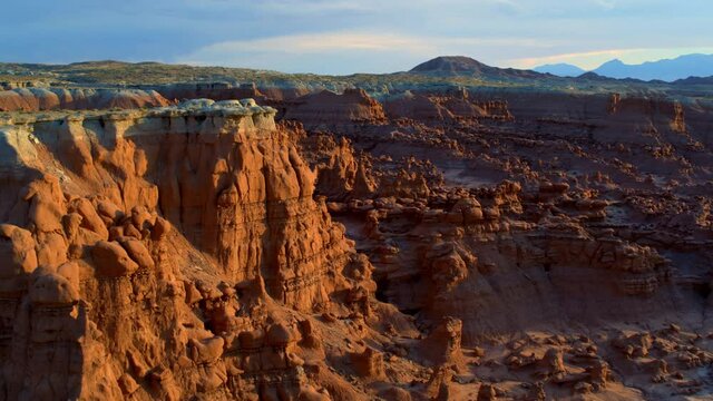 Wide aerial, sunset over Goblin Valley mountains