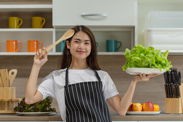 Happy young Asian woman cooking with fresh vegetable in the modern kitchen