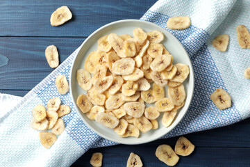Heap of sweet banana slices on  a plate on a blue wooden  background. Dried fruit as healthy snack