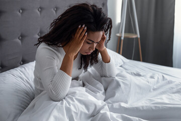 Black woman suffering from headache or migraine in bed
