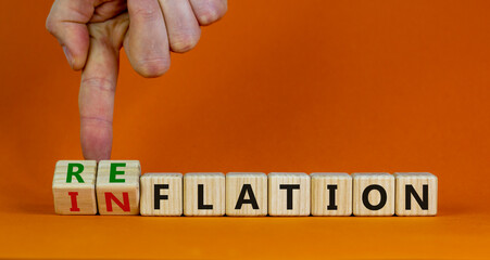 Inflation or reflation symbol. Businessman turns cubes and changes the word inflation to reflation. Beautiful orange background, copy space. Business, inflation or reflation concept.
