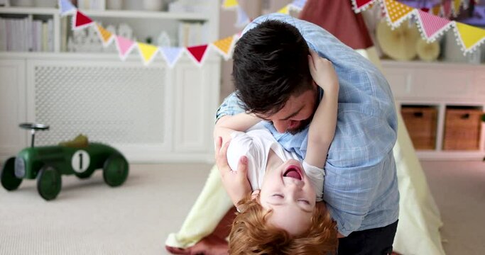 happy father playing with laughing kid, family having fun at home