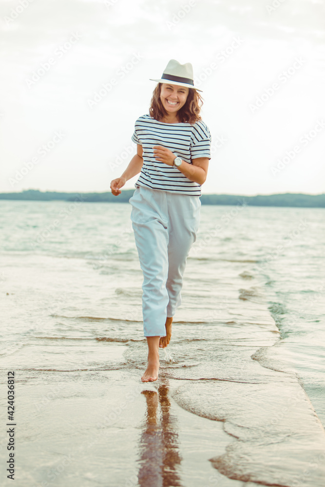 Wall mural woman in white clothes walking by sea beach