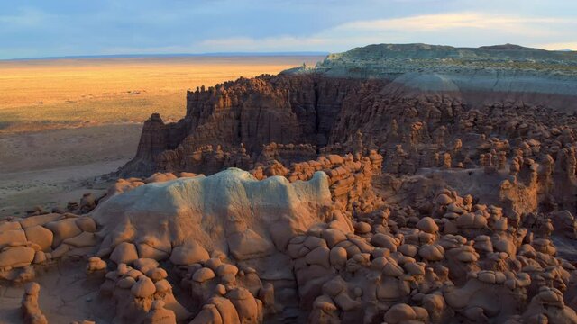 Wide aerial, open desert mountains in Goblin Valley at sunset